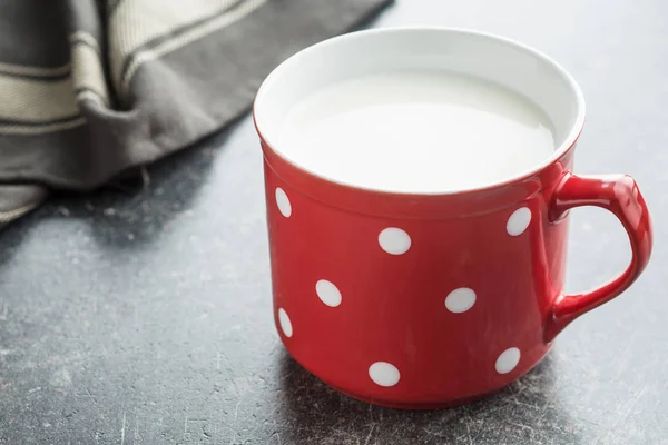 Leite em caneca vermelha com manchas brancas . — Fotografia de Stock