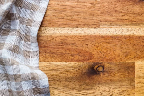 Geruit tafelkleed over houten tafel. — Stockfoto
