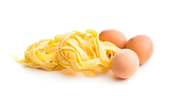 Raw tagliatelle pasta and three eggs. — Stock Photo, Image