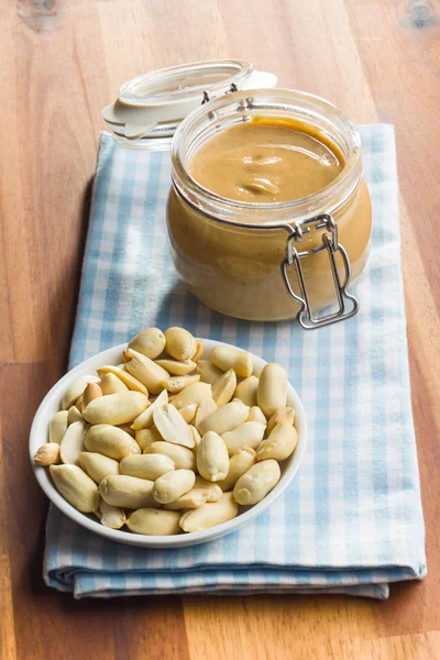 Mantequilla de cacahuete en frasco y cacahuetes . — Foto de Stock