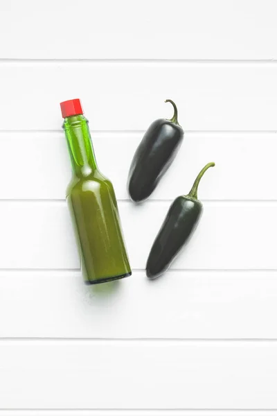 Green jalapeno peppers and tabasco sauce. — Stock Photo, Image
