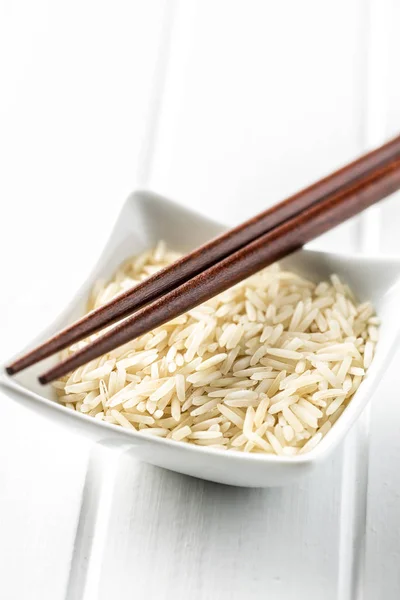 Uncooked indian long rice in bowl and chopsticks. — Stock Photo, Image