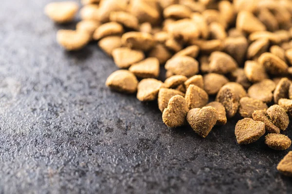 Dried kibble pet food. Heart shape dried animal food on old table.