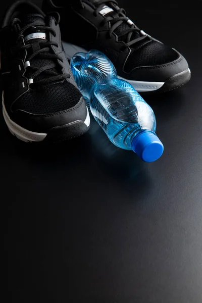 健康的概念 黑色运动鞋和黑色背景的瓶装水 — 图库照片