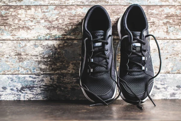 Eski Ahşap Duvarın Önünde Siyah Spor Ayakkabılar — Stok fotoğraf