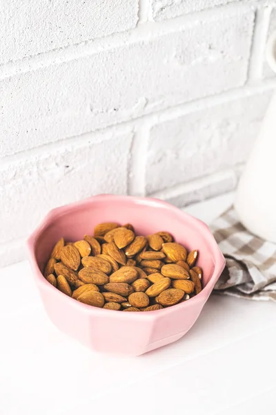 Nueces Almendras Secas Tazón Sobre Mesa Blanca Ante Pared Ladrillo — Foto de Stock