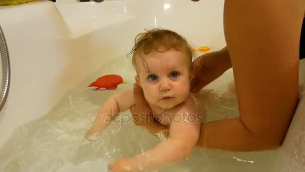 Новорожденный ребенок играет и улыбается в ванной — стоковое видео