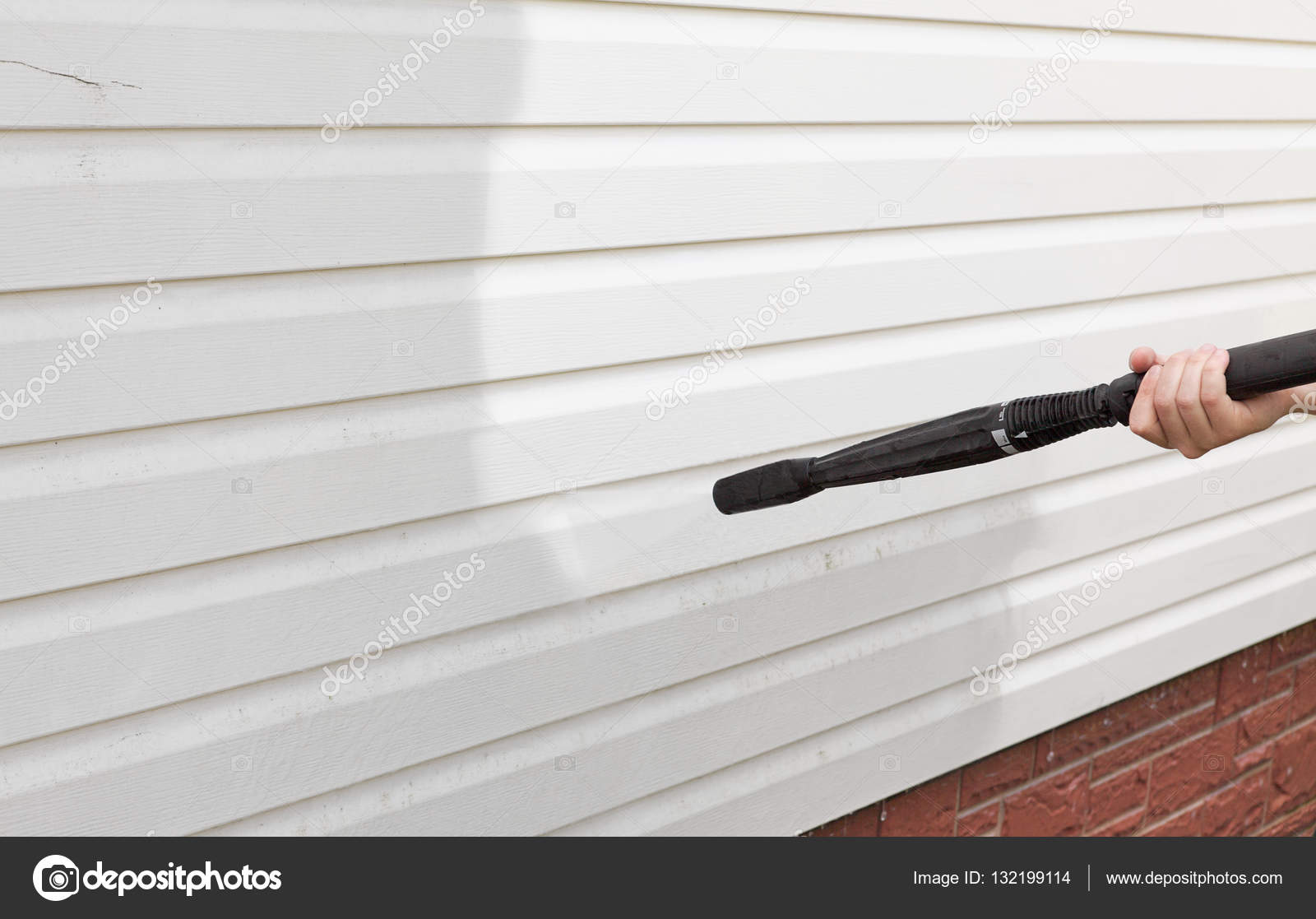 Cleaning the wall (vinyl siding) high pressure cleaner Stock Photo by