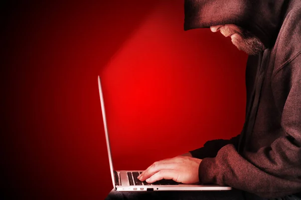 戴兜帽的计算机黑客红色背景 — 图库照片