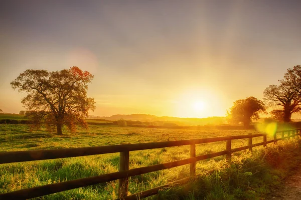 Nascer do sol rural sobre o campo cercado — Fotografia de Stock