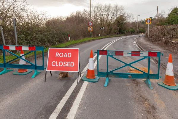 Road closed with barrier and signage. Rural highway shut with signs and safety fences.