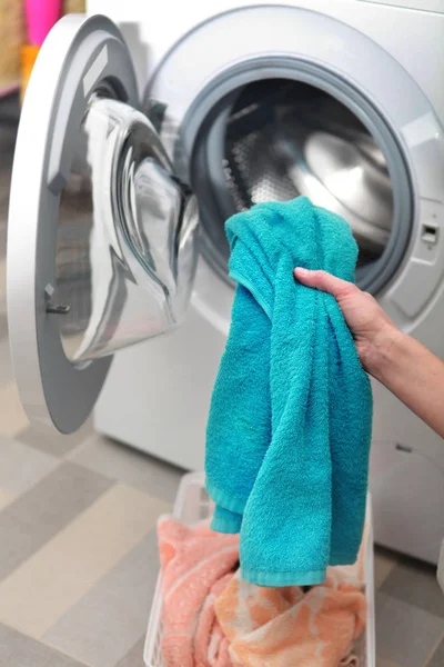 Женщина загружает одежду в стиральную машину — стоковое фото