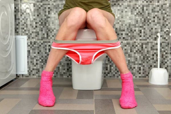 Woman sits on toilet bowl — Stock Photo, Image