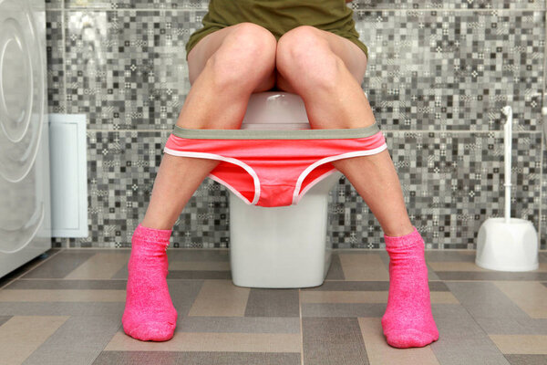 woman sits on toilet bowl