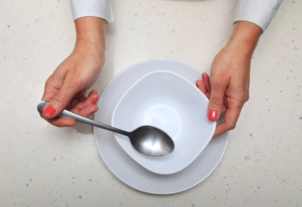 Woman holds spoon and plate — Stock Photo, Image
