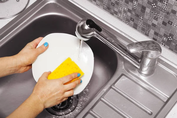 Жінка, яка миє білу тарілку — стокове фото