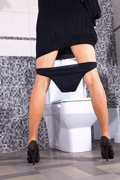 Back of woman that stays near toilet bowl Stock Image