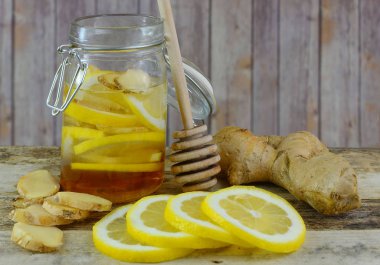 Doğal soğuk veya grip ilacı zencefil, içeriği için portre resim malzemelerin tatlım bir kavanoz, bal drizzler ve ahşap arka plan üzerinde limon.