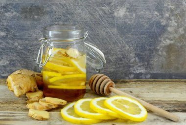 Portre resim maddeler doğal soğuk veya grip çare için zencefil, bal ve limon bir sıkıntılı, rustik çelik arka plan ile ahşap bir masa üzerinde bir kavanoz dahil edilir.