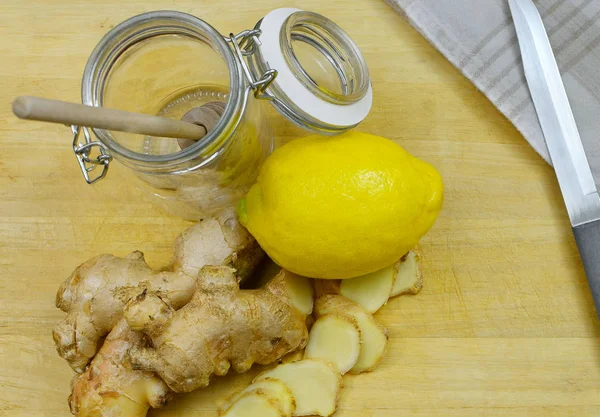 Portre opverhead yansıması doğal soğuk veya grip çare için malzemelerin zencefil ve limon ahşap arka plan üzerinde içerir. Sahne bir soyma bıçağı ve boş kavanoz ve vintage havlu içerir.