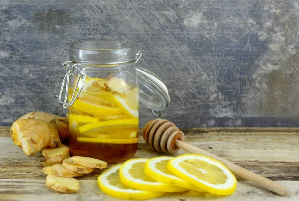 Portre resim maddeler doğal soğuk veya grip çare için zencefil, bal ve limon bir sıkıntılı, rustik çelik arka plan ile ahşap bir masa üzerinde bir kavanoz dahil edilir.