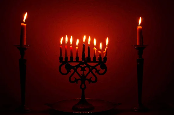 A menorah filled with lit candles and flanked by two single candles for the Jewish holiday, Hanukkah in December