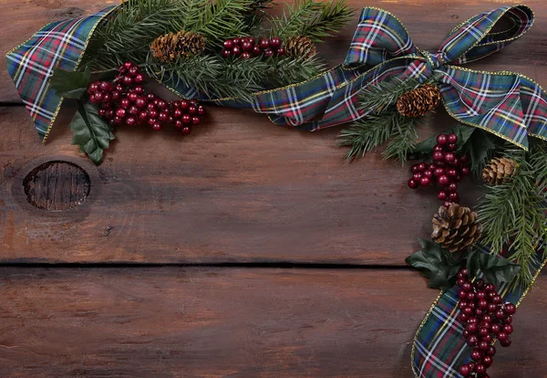 Çam ağaçları, böğürtlenler ve geniş tahta bir arka planda neşeli bir ekose kurdele ile kırsal Noel sınırı. Boşluğu kopyala.