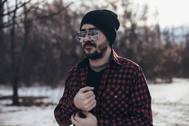 Siyah bir şapka ve güneş gözlüğü parkta giyen güzel esmer adam ekose gömlekli sakallı