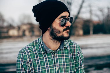 Siyah bir şapka ve güneş gözlüğü parkta giyen güzel esmer adam ekose gömlekli sakallı