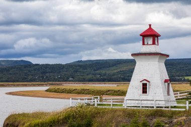 Anderson Hollow lighthouse by the Shepody River dam in Harvey, Bay of Fundy, New Brunswick. Beautiful summer day with calm water and cloudscape. clipart