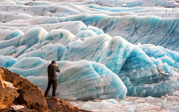 男はアイスランド南東部のSvinafellsjokul氷河で青い氷河の氷を撮影します これはヨーロッパで最大の氷冠です — ストック写真