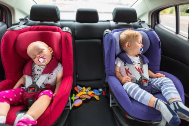 Little boy and girl twins in the car safety seat