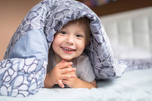 Baby boy hiding in bed — Stock Photo, Image
