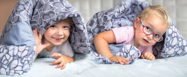 Bliźniaki chłopiec i dziewczynka dziecko ukrywa się w łóżku — Zdjęcie stockowe