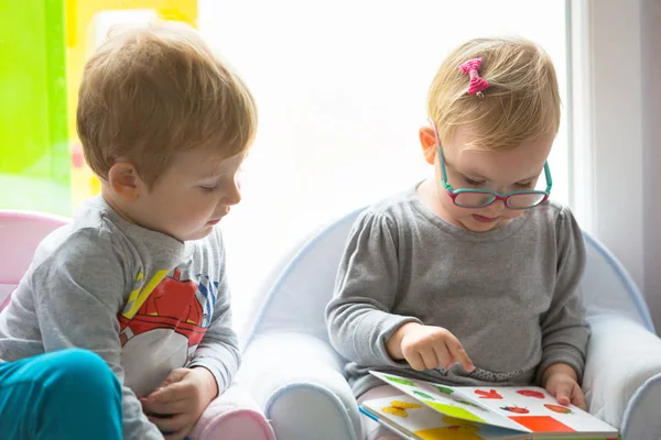 Хлопчик і дівчинка близнюки читають книгу разом — стокове фото