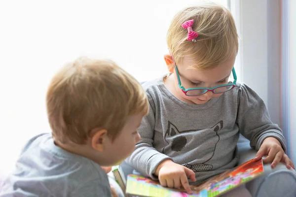 Niño y niña gemelos leyendo libro juntos —  Fotos de Stock