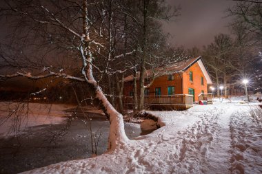 Küçük yazlık evi yakın göl karlı gece, İsveç