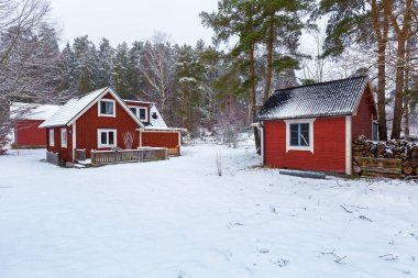 Winter scenery with red wooden house in Sweden clipart