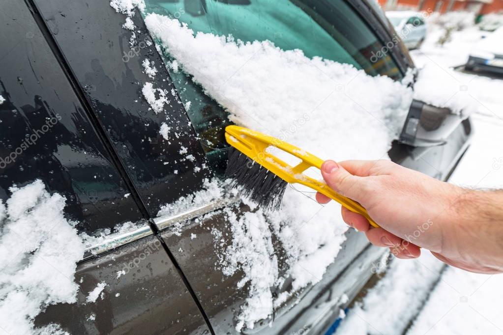 Scraping frozen snow from the car windows