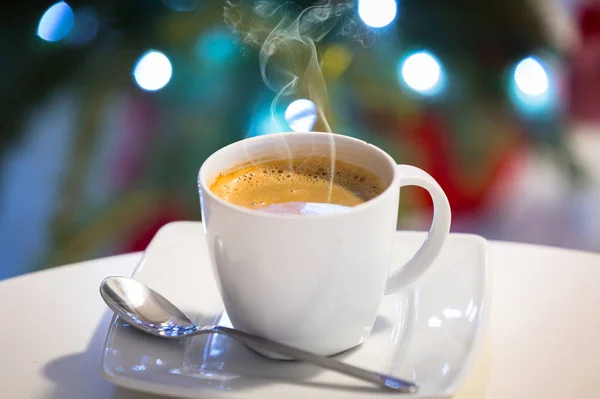 一杯热咖啡放在桌子上 背景上挂着圣诞树灯 — 图库照片