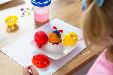 Paskalya yumurtaları boyayan küçük kız