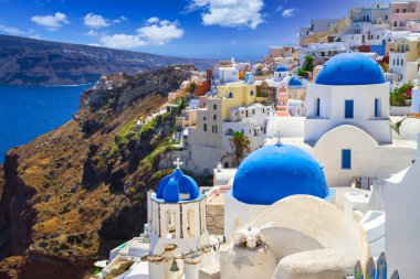 Blue church domes and white houses in the beautiful Oia town on the Santorini island, Greece. clipart