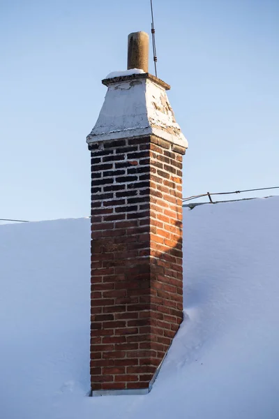 Chaminé de tijolo velho e telhado coberto com neve — Fotografia de Stock