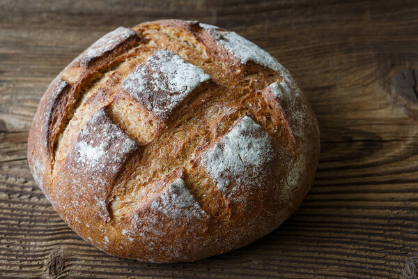 A freshly baked rustic, loaf of bread on an old wooden table