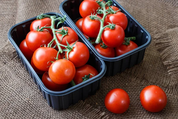 Cherry tomaten in een plastic container op bruine achtergrond — Stockfoto