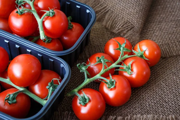 Cherry tomaten in een plastic container op bruine achtergrond — Stockfoto