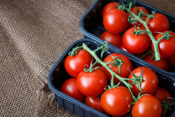 Cherry tomaten in een plastic container op bruine achtergrond — Stockfoto