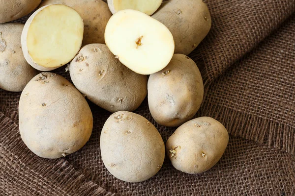 Pilha de batatas velhas com brotos no fundo marrom — Fotografia de Stock