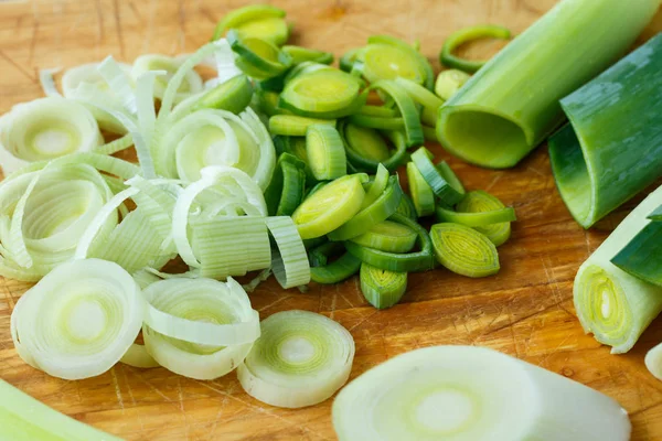Fresh leeks whole and sliced on a wooden kitchen board — Stock Photo, Image