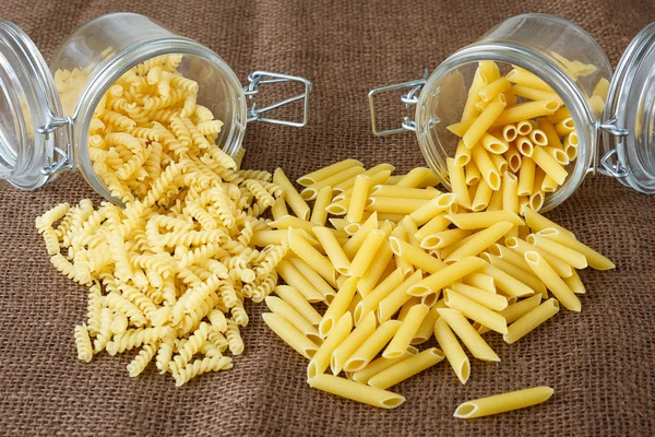 Italian pasta - penne and fusilli in glass jar — Stock Photo, Image